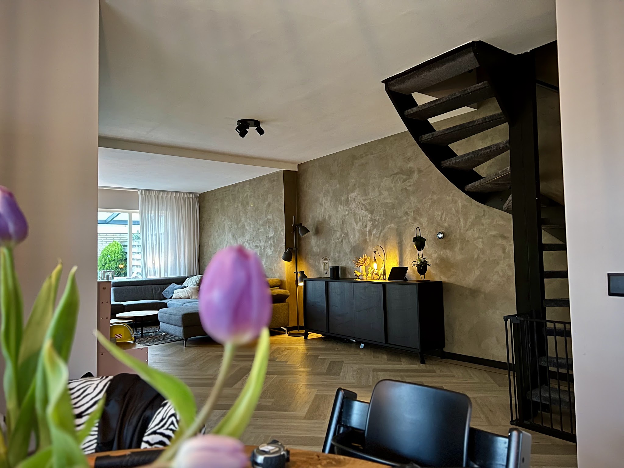 Woonkamer met design stucwand en een zwarte wenteltrap